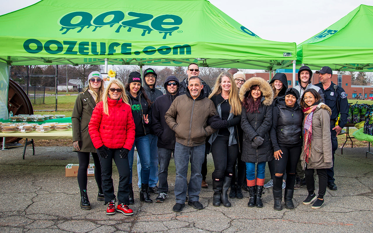 The Ooze Wholesale team is standing in front of their tents at the Oozegiving event. 200 turkeys, pies and side dishes were distributed as a Thanksgiving feast for 200 Detroit families in need.