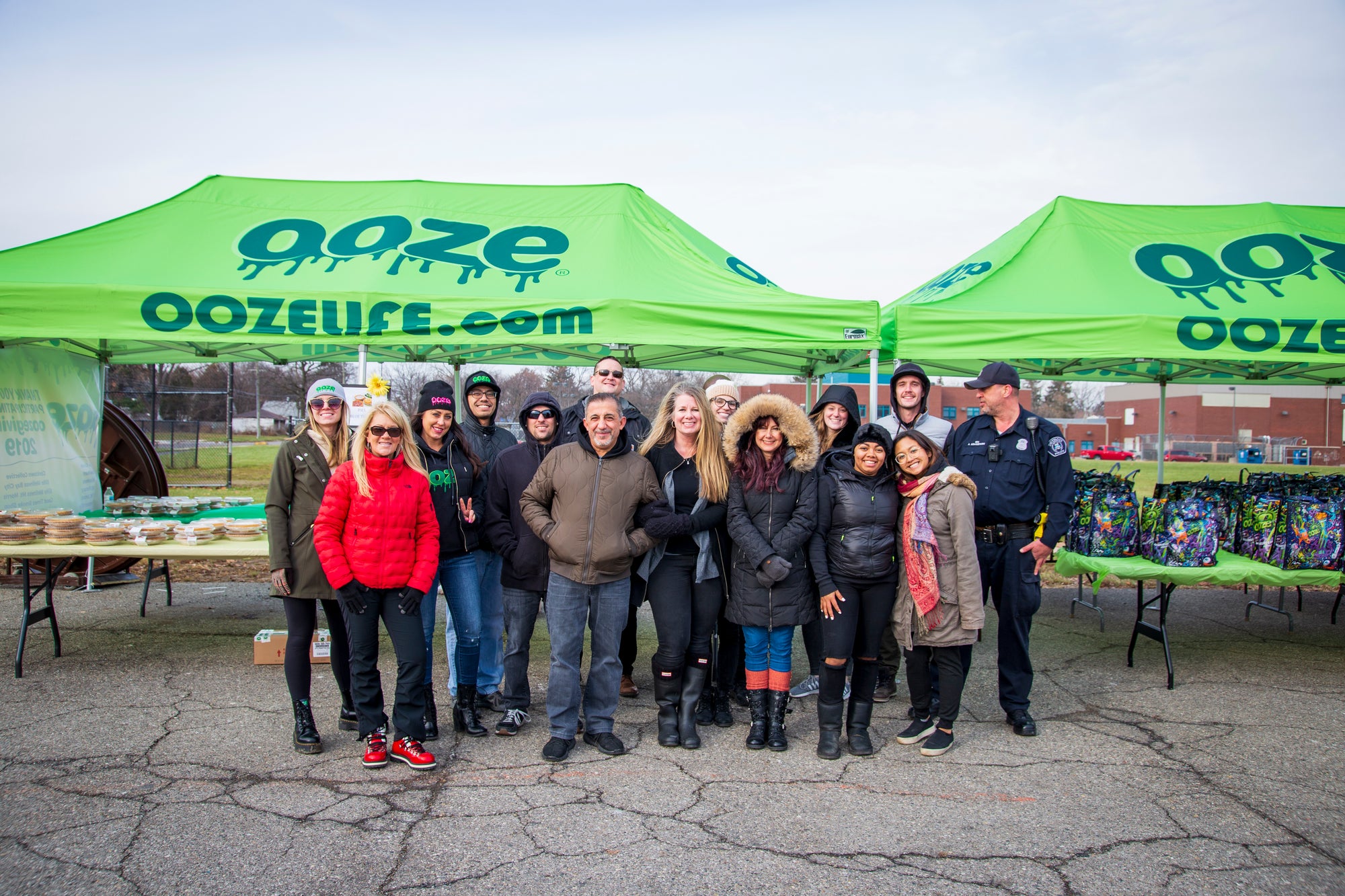 The Ooze Foundation team is posed for a group photo in front of the Ooze tents and tables full of food at the Oozegiving food drive event in Detroit.